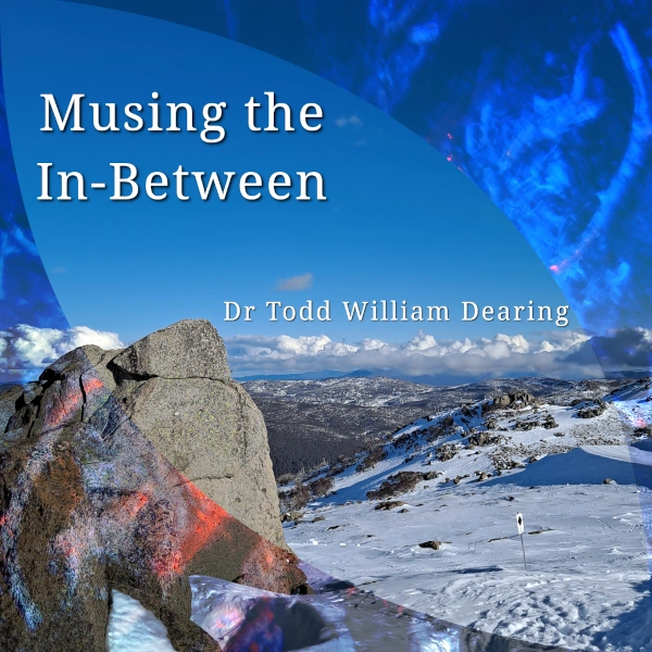 Musing the In-Between, front cover, showing a mountainous landscape with snow and rocks, combined with ancient inscriptions around the border.